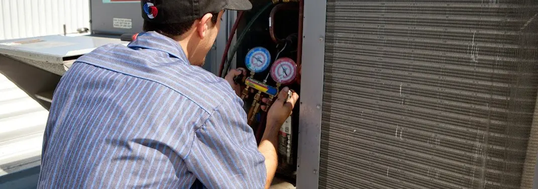 HVAC technician servicing a condenser unit in Downey